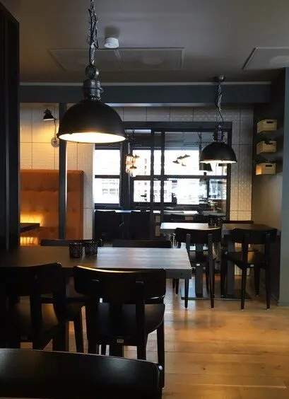 Tavernan Alta: mørk spisesal med svarte pendellamper, benk i brunt skinn og hvite fliser på veggen