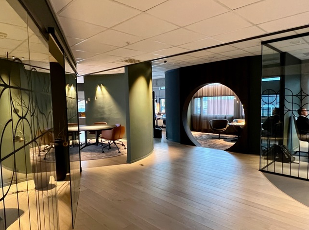 Atea kontorer – Frydenbø Eiendom: kontor med glassvegger, sittegrupper og en rund åpning inn til et rom med gardiner